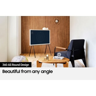 The Serif is on a stand next to a chair and small table.