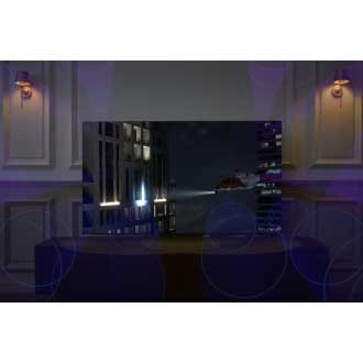 A Neo QLED TV is displaying a helicopter shooting light onto a building at night. Sound waves from its top channel speakers are filling the room.