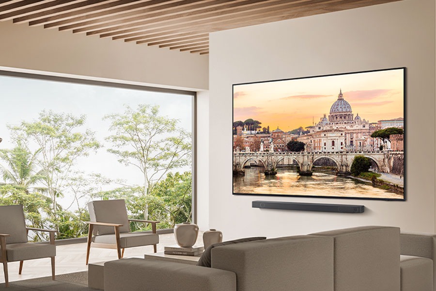 QN85D wall-mounted with Soundbar in natural living room.