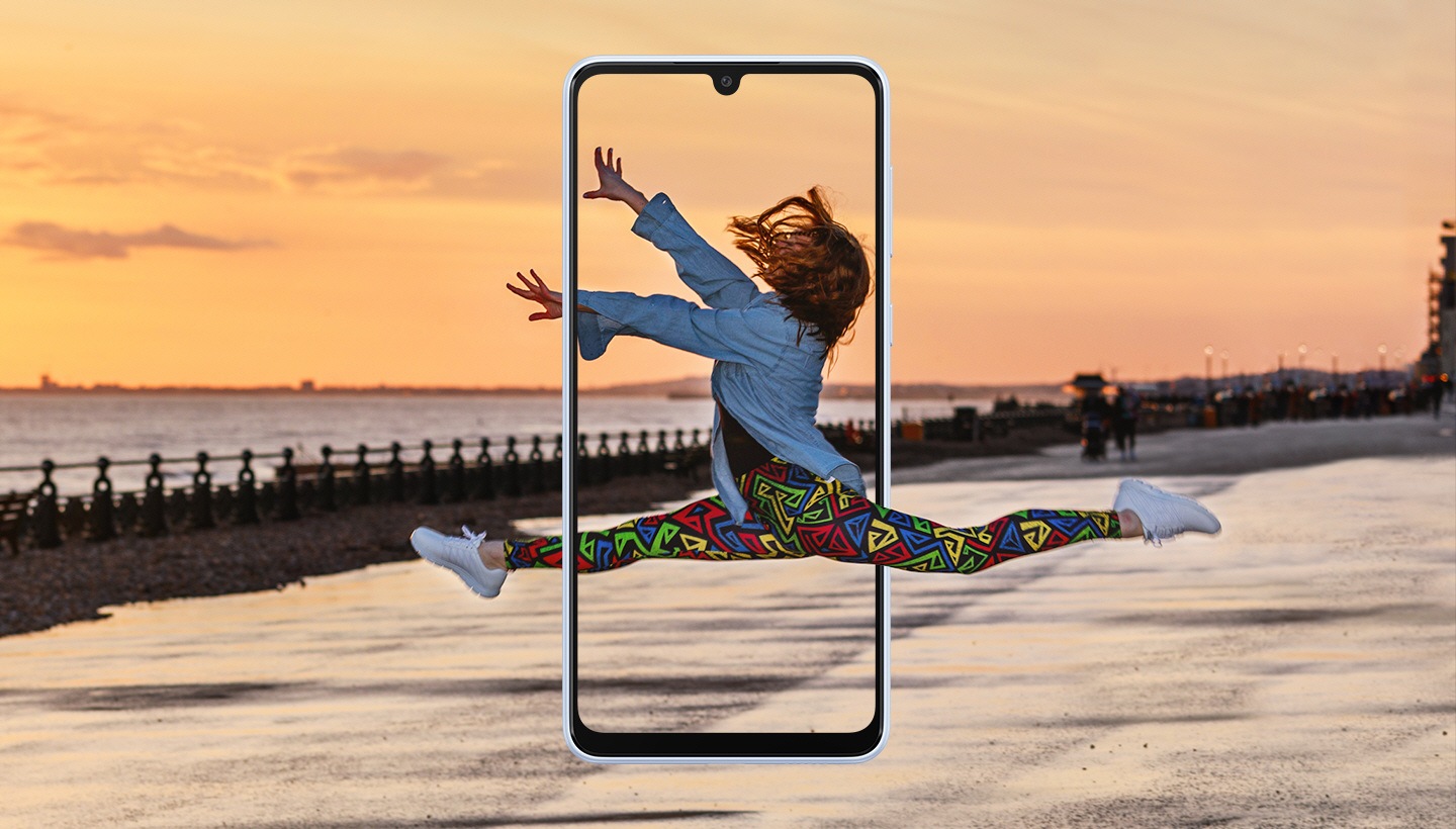 Zabilježena je žena usred skoka koji nalikuje baletskom pokretu. Pejzaž u pozadini prikazuje predivan pogled na zalazak sunca a Galaxy A33 5G je u sredini i uokviruje ženu usred skoka.