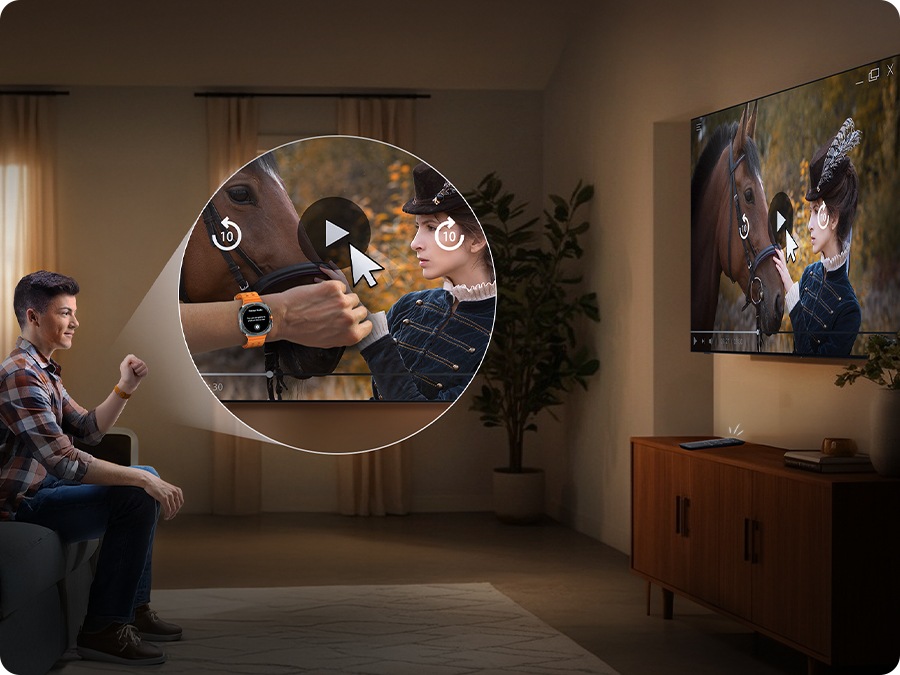 Man wearing a Galaxy Watch watches TV in a living room. He moves his hand back and forth to play the video on the screen.