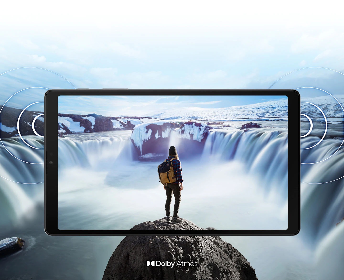 Galaxy A7 Lite seen from the front with an image of a person standing on a rock in front of steaming waterfalls on either side onscreen. The image expands past the edges of the tablet to show the expansiveness of the display. Rings come out from the sides to demonstrate the location of the dual speakers and the immersive sound of Dolby Atmos.