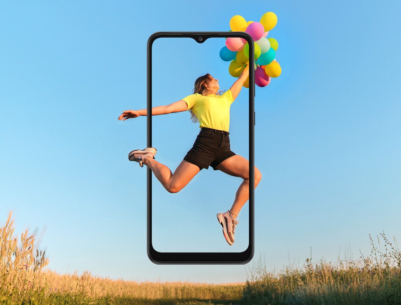 A girl is jumping up with a bundle of balloons in her hands, with the wide open sky in the background. The Galaxy A03 Core's large screen frames her entire body, with her foot and part of her calf outside it.