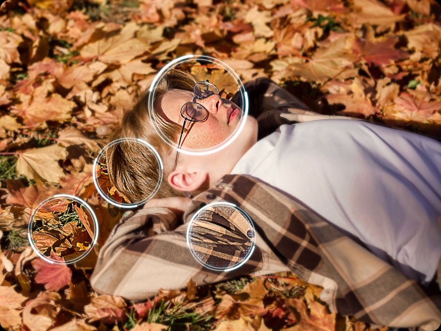 Image of a little boy laying on the ground covered in fall leaves. Several differents points are detected, including the boy's face, hair, clothes and leaves, and then upscaled to 4K resolution, along with the rest of the image. The result is a much sharper image where subtle details are visible.