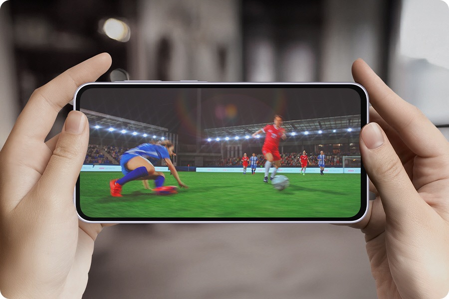 On peut voir le texte Octa Core. L'image effectue un zoom arrière et affiche le texte Octa Core à l'écran avec une personne tenant le Galaxy A36 5G horizontalement. L'écran passe ensuite à la vidéo d'un match de football.