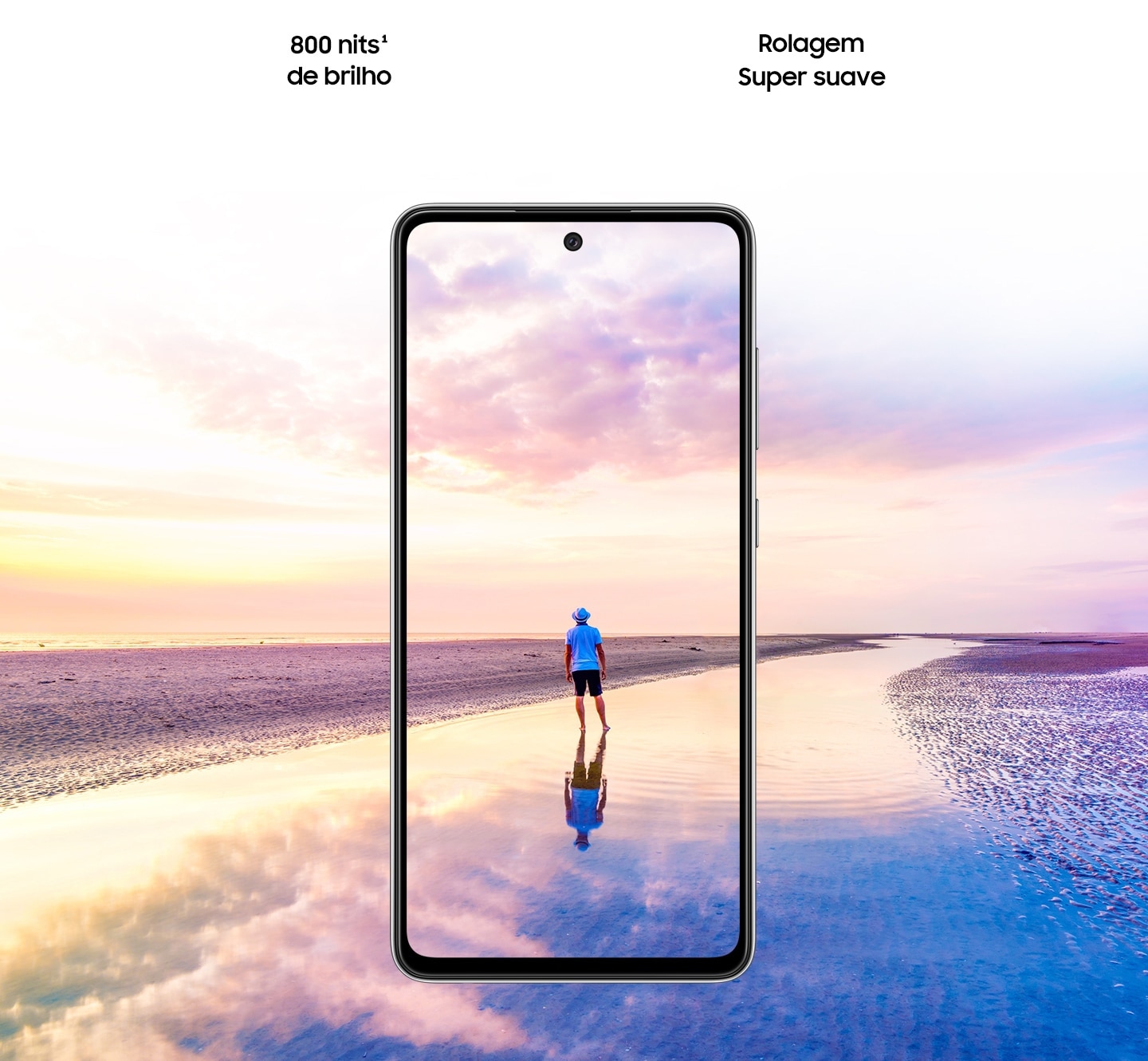 Vista frontal do Galaxy A52. Uma cena de um homem em pé em uma praia ao pôr do sol com cores rosa e azul no céu se expande para fora do display. O texto diz 800 nits de brilho, Eye Comfort Shield, com o logotipo da SGS e do Real Smooth.