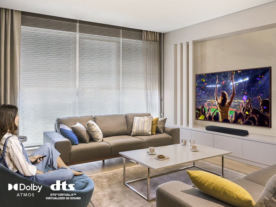 A woman enjoys a music concert on her TV. Simulated sound wave graphics illustrate the immersive 3D sound experience of Samsung S series soundbar. The dts virtual X logo can be seen.