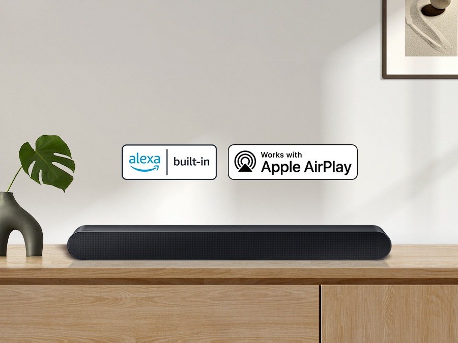 Alexa logo and Apple AirPlay logo can be seen along with Samsung S60B soundbar which is sitting on living room cabinet.