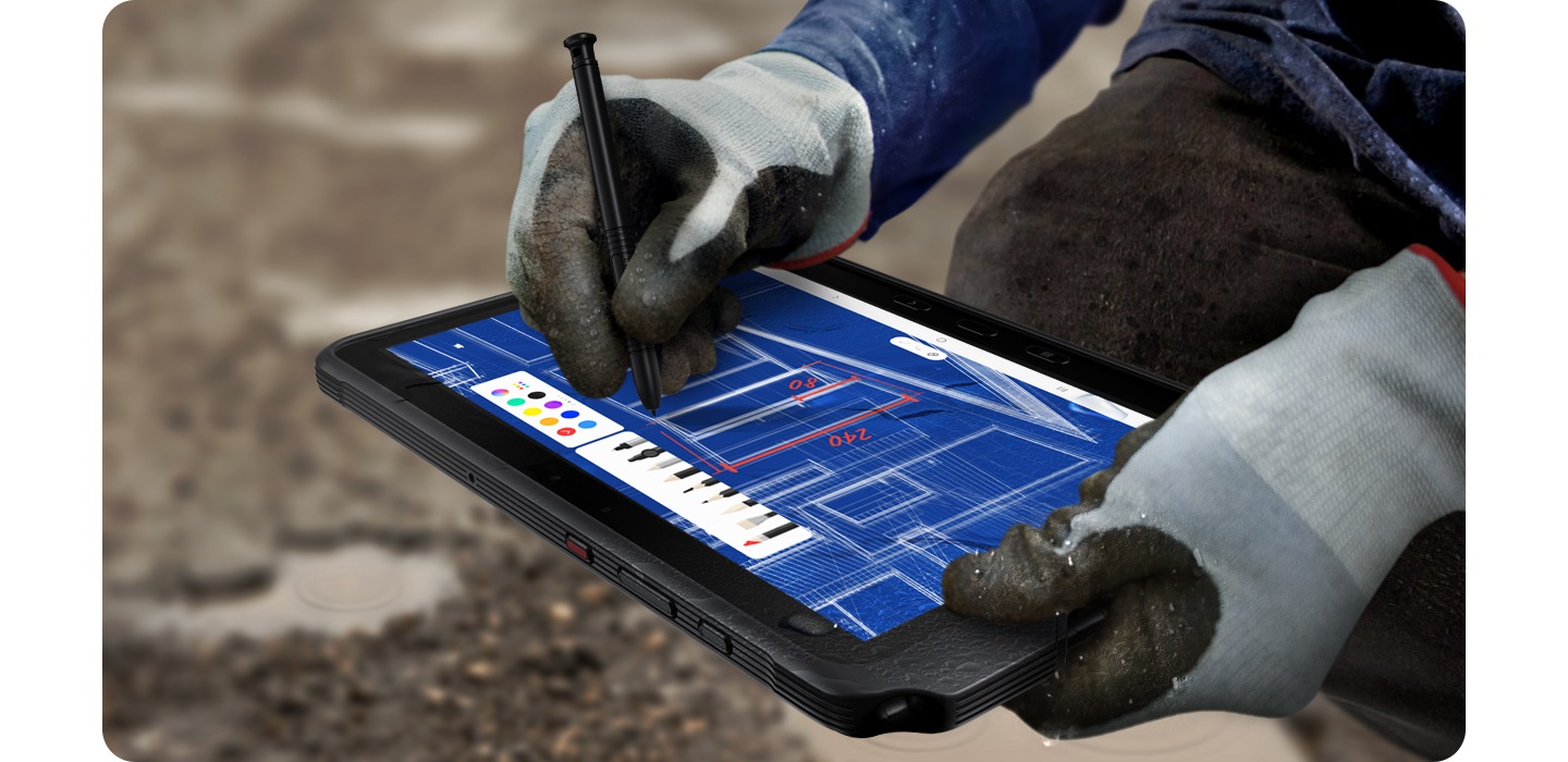 Робочий на вулиці в рукавичках креслить план за допомогою Galaxy Tab Active4 Pro та S Pen