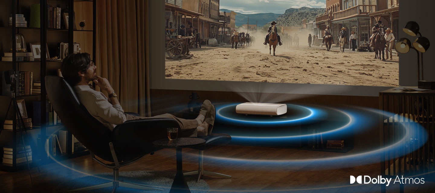 A man watches a Western movie being projected by The Premiere. The Premiere lets out waves of sound from the movie. Dolby Atmos logo.