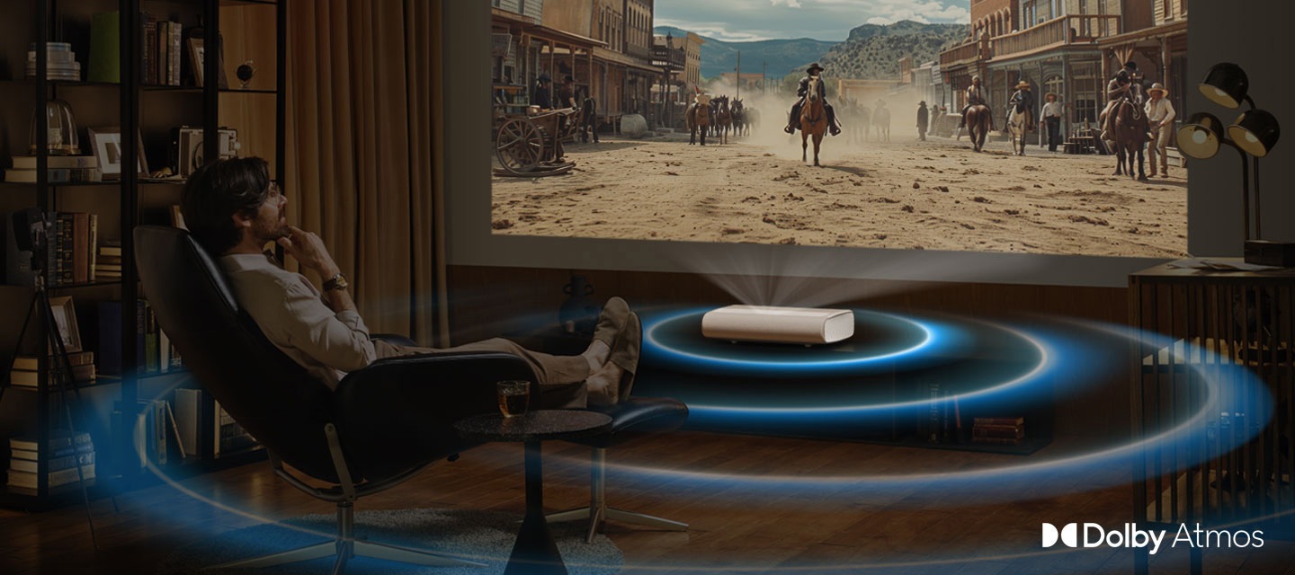 A man watches a Western movie being projected by The Premiere. The Premiere lets out waves of sound from the movie. Dolby Atmos logo.