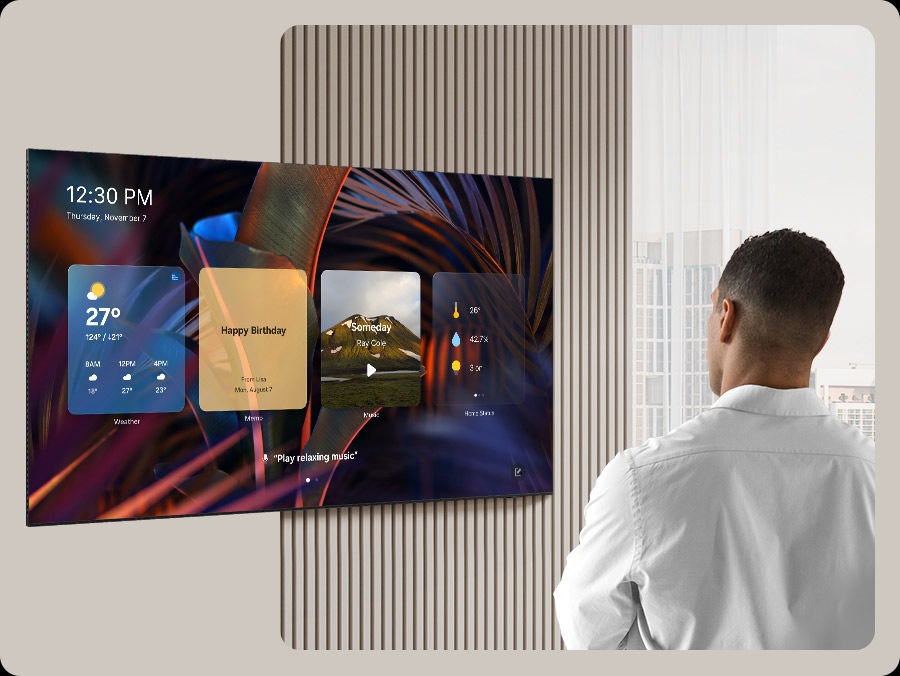 A man looks at a blank TV screen. The screen activates to display Daily Board, which shuffles through widgets for Weather, Memo, Music, Home Stats, Samsung TV Plus and Tips. It also displays the time and date, along with a voice prompt to play relaxing music.