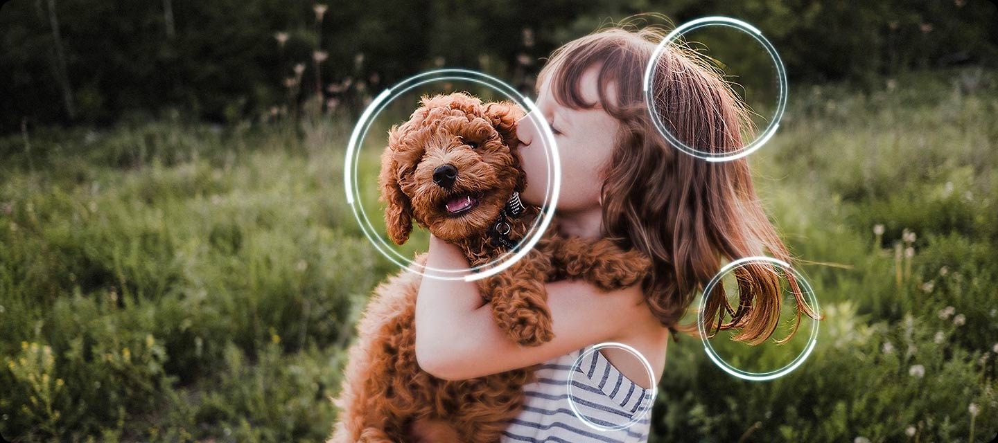 Image of a little girl kissing a puppy. The Samsung NQ4 AI Gen3 Processor appears on the photo and enhances several details, including the girl’s hair and clothes and the puppy’s face. The result is a much sharper image where subtle details are visible.