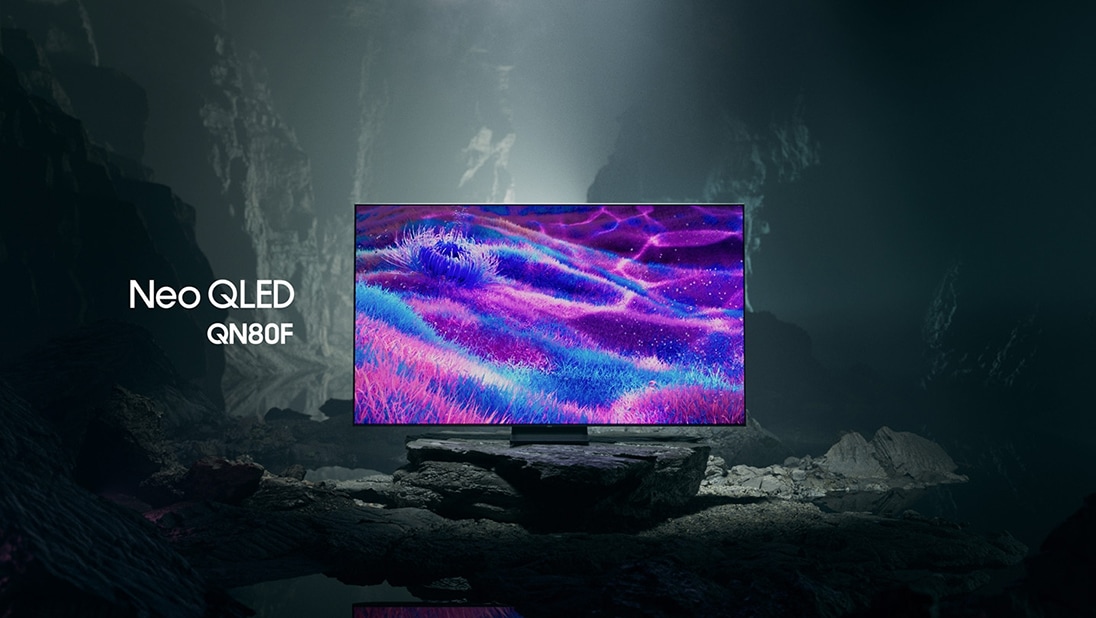 Samsung Neo QLED QN80F TV in a black and white underground space displays a colourful scene of an otherworldly landscape.