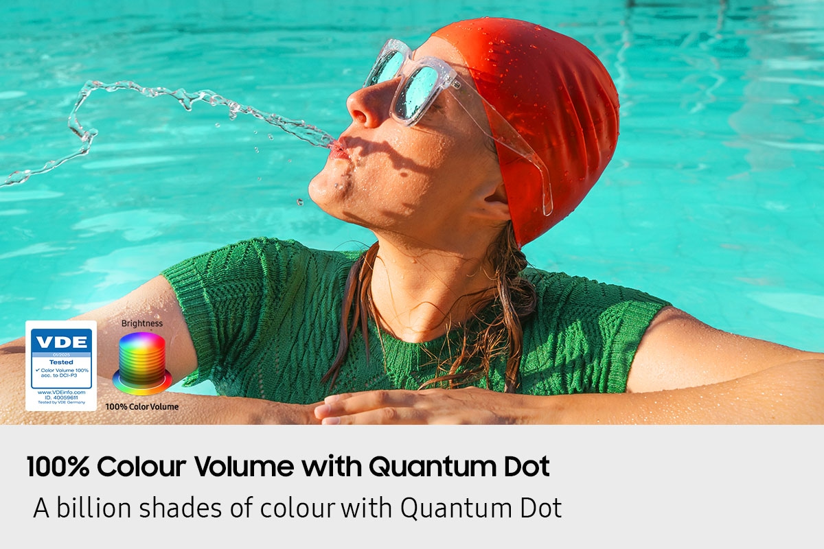A scene of a woman in a pool spitting out water. Logo reads VDE 01/2025 Tested Color Volume 100% acc. to DCI-P3. www.VDEinfo.com. ID 40059611. Tested by VDE Germany. Another logo is made of stacked color wheels that represent Brightness. 