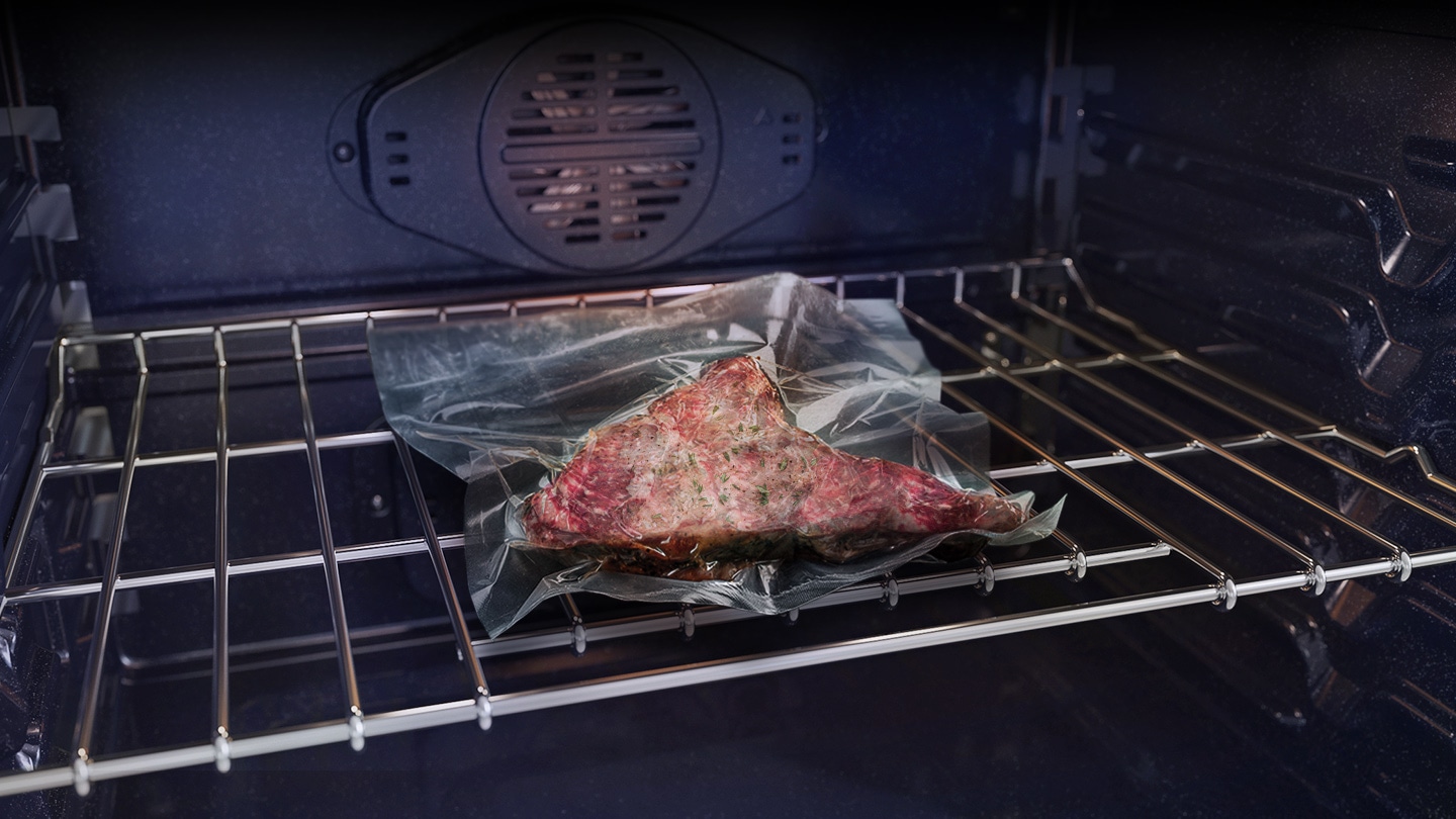 It shows raw meat inside a vacuum-sealed pack being cooked at a low temperature inside the oven.
