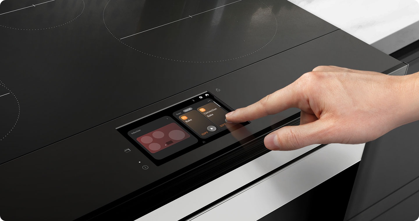 There is a closeup of an induction range cooktop with an LCD display. A hand is touching the LCD panel.