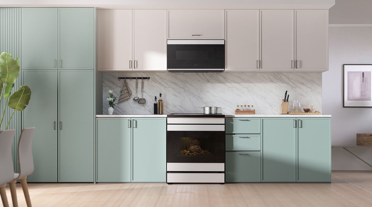 An induction range installed in a spacious, sun-lit contemporary kitchen with blue and white cabinets.