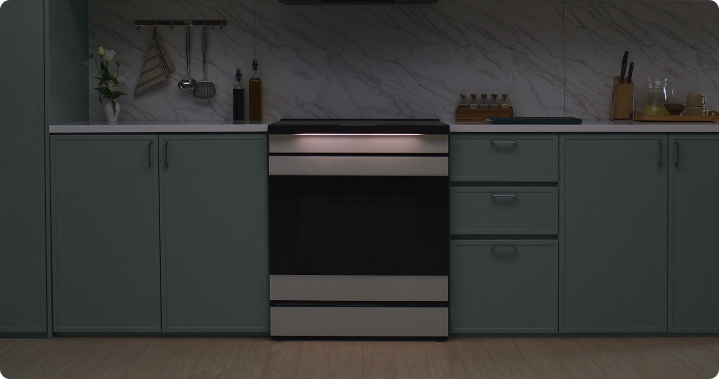 An induction range is placed in a dimly lit contemporary kitchen. The motion of the ambient light under the cooktop indicates the cooking status.