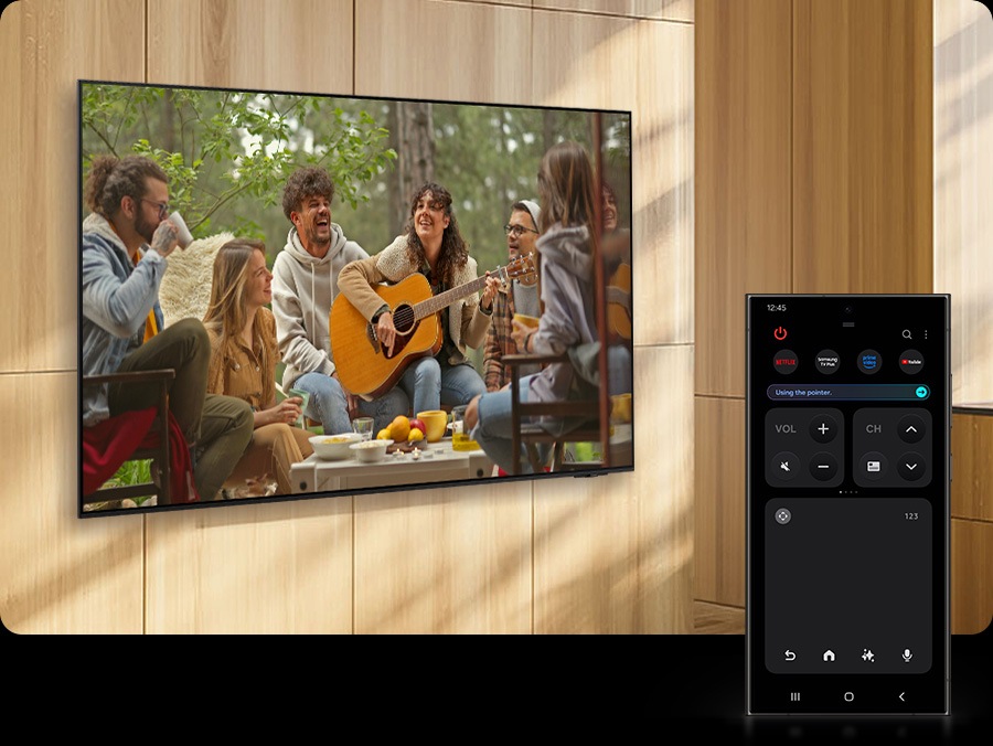 Un téléphone intelligent Galaxy affiche le mode Télécommande rapide, qui est utilisé pour augmenter le volume d’un téléviseur à proximité, alors qu’il montre une scène d’une femme jouant de la guitare.