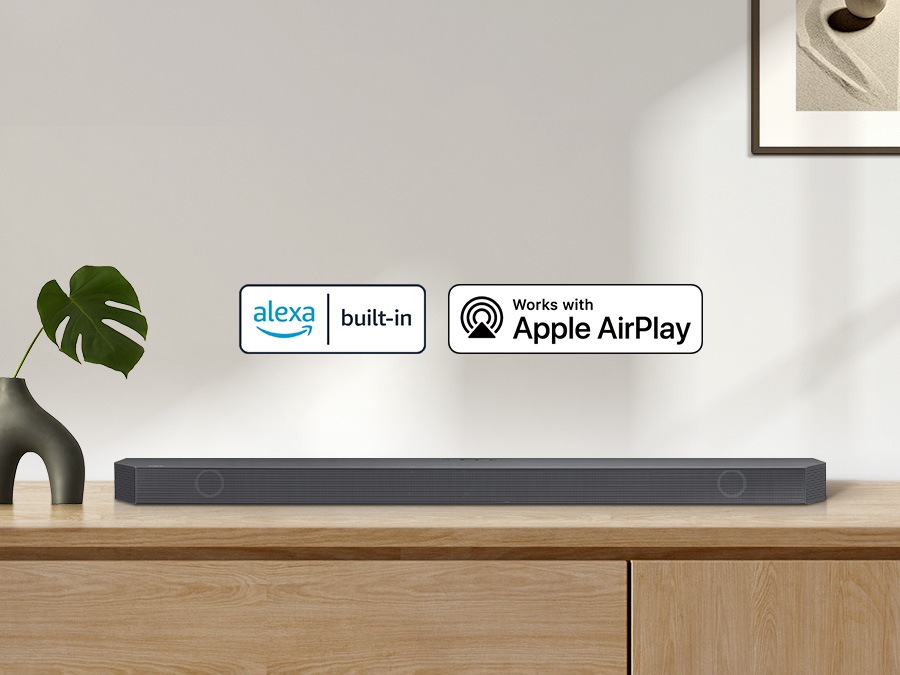 El logotipo de Alexa y el logotipo de Apple AirPlay pueden estar junto con la barra de sonido Samsung Q800B, que está sentada en el gabinete de la sala de estar