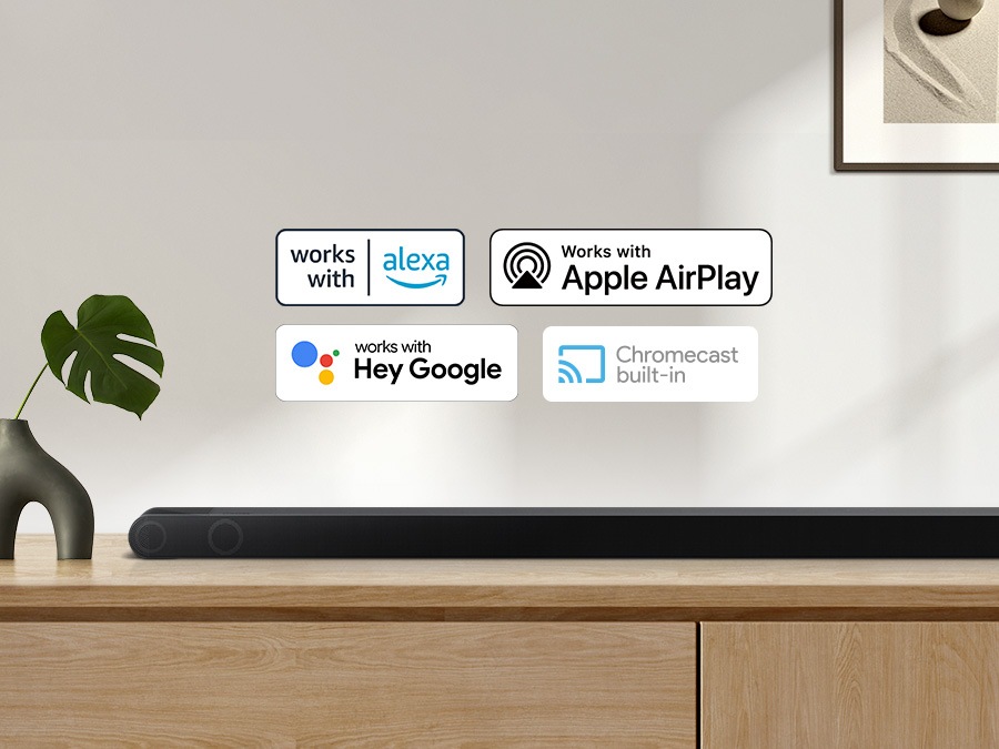 Alexa-logotyp, Apple Airplay-logotyp, Hey Google-logotyp och Chromecast inbyggd logotyp kan vara tillsammans med Samsung S800B-ljudfält som sitter på vardagsrumskåpet