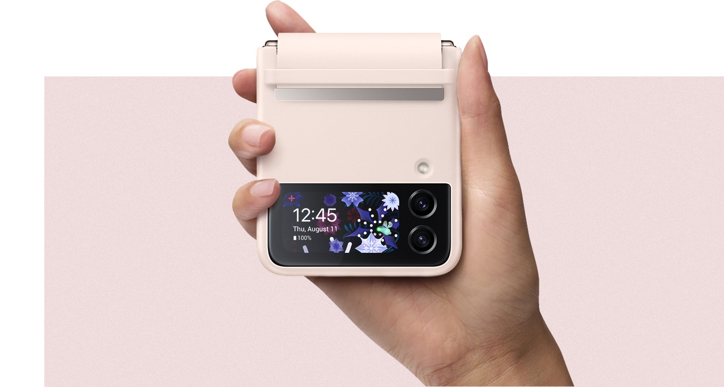 Une main tient un appareil Galaxy Z Flip4 équipé d'une coque en cuir avec rabat en coloris Peach, montrant le côté de l'écran extérieur.