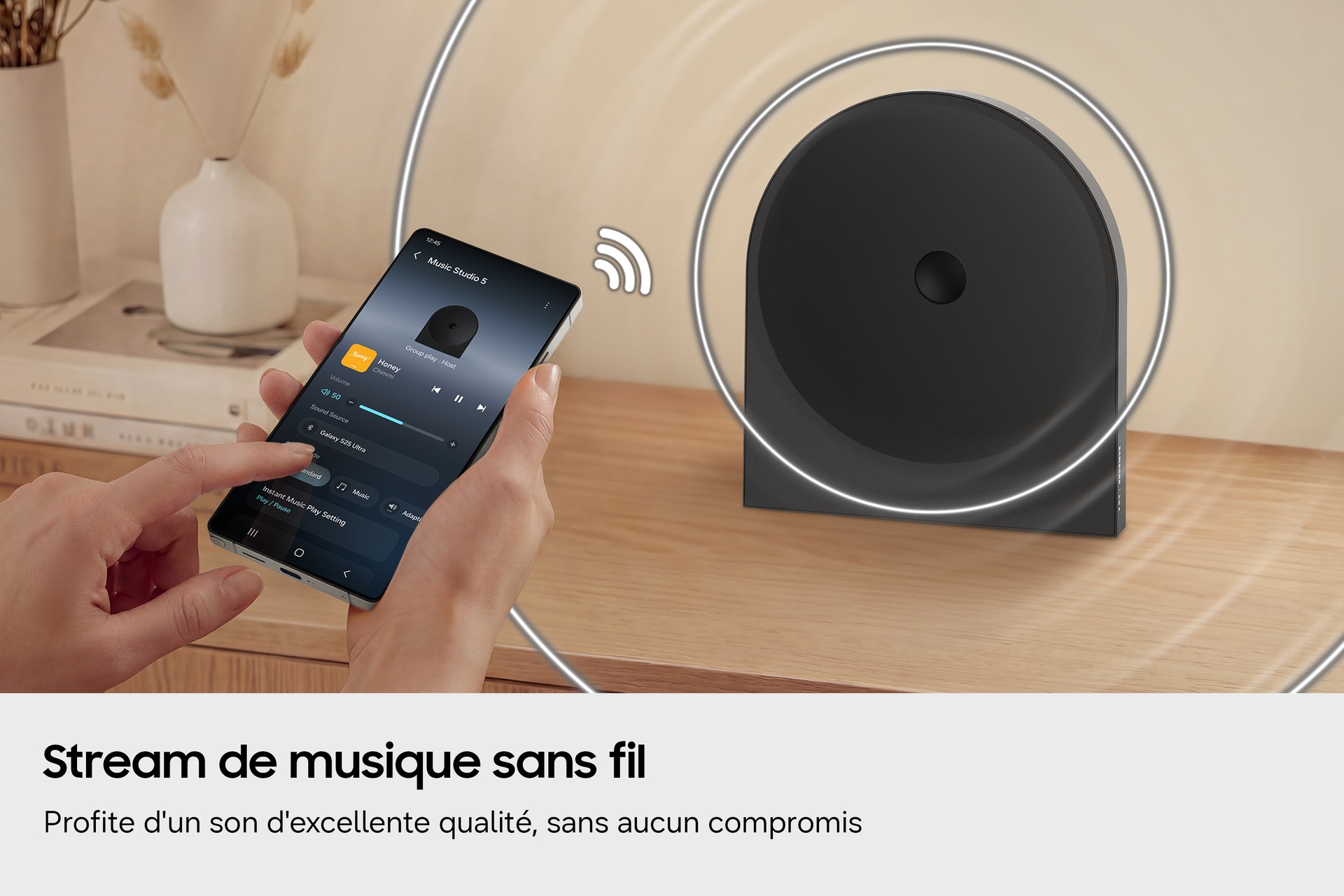 Une personne utilise un smartphone pour diffuser de la musique sans fil vers le Music Studio 5 posé sur une table en bois. 