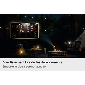 Samsung The Freestyle+ projette de nuit, en plein air sur un terrain de camping, une scène de jeu vidéo sur un écran, démontrant ainsi ses possibilités d'utilisation dans différents lieux.