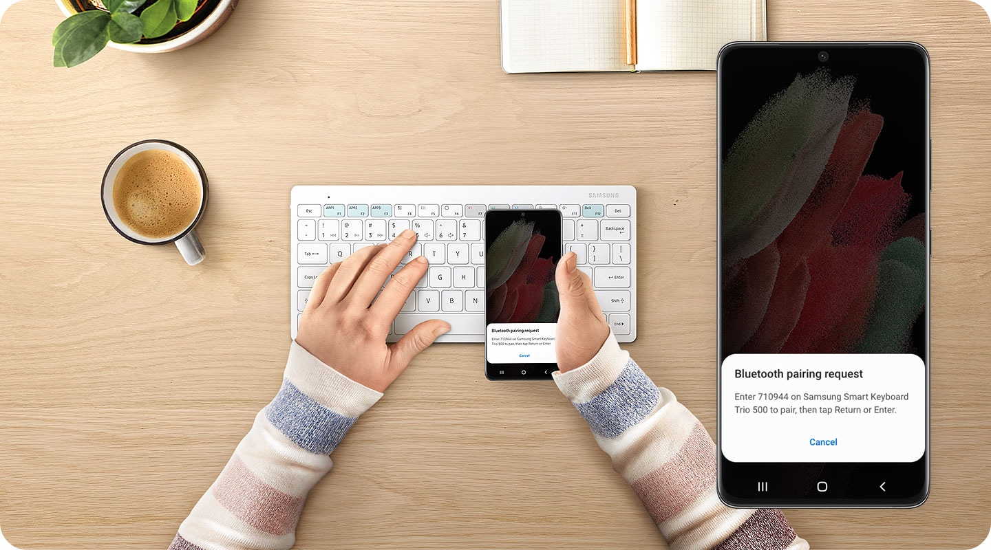 There is a white-colored Samsung Smart Keyboard Trio 500 on a desk. Above it, a left hand is typing the 6-digit key which allows it to pair with a smartphone. A right hand is grabbing a smartphone, on which it shows the easy-pairing pop-up writtened 6-digit key. On the right side, there is a close-up of what is on-screen on the phone.