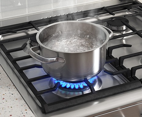 Muestra una olla con agua sobre la placa de cocción, que se está hirviendo en el quemador Rapido.