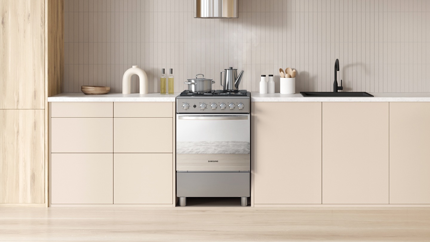 Shows the oven, with a mirror finish and flat handle, fitted harmoniously between the cabinets of a modern looking kitchen.