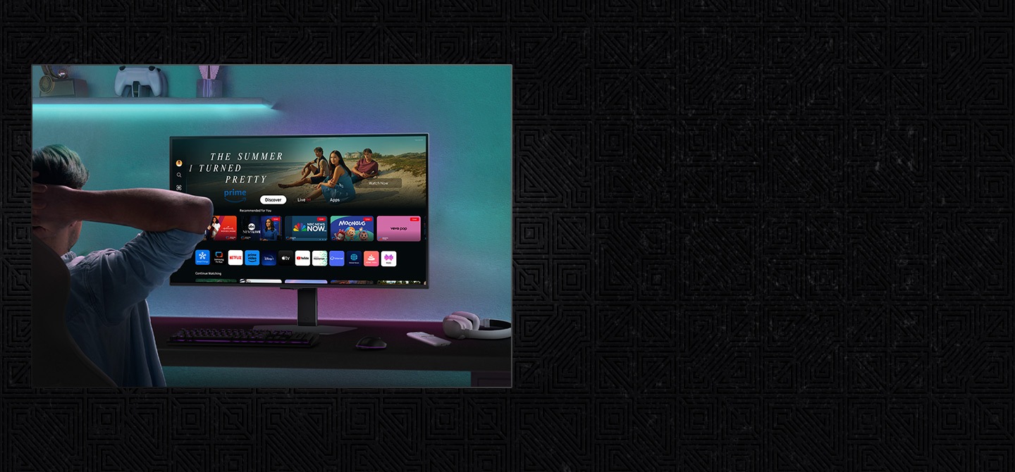 Un jugador se reclina en su silla frente al monitor, revisando la pantalla doméstica Smart Hub con opciones de aplicaciones de vídeo como Netflix y Amazon Prime.