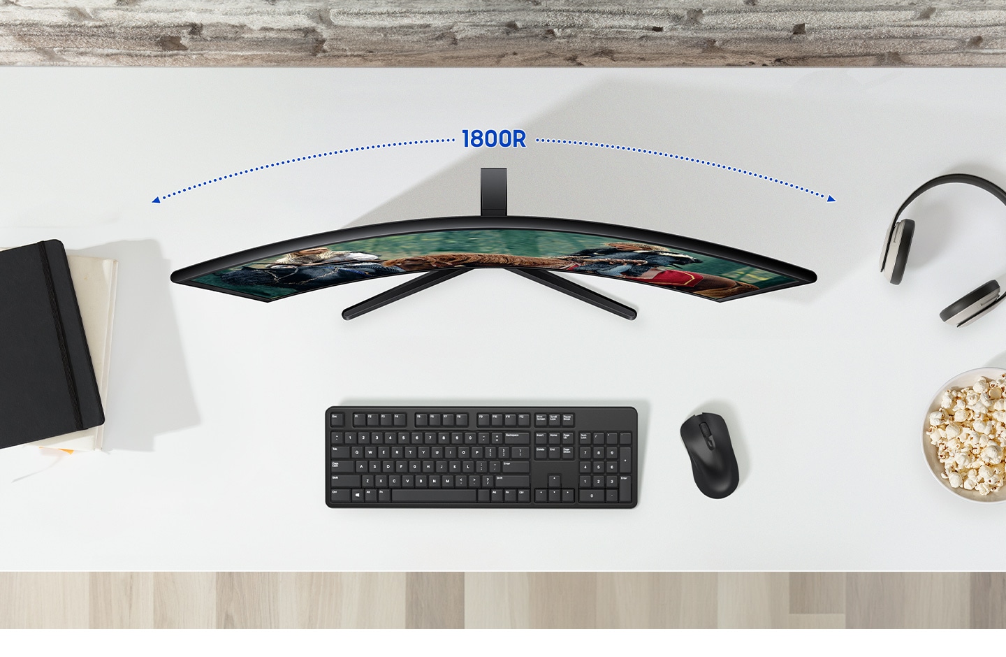 A monitor is on the desk, and there are some peripherals around it. Above the monitor its curvature - 1800R is marked.