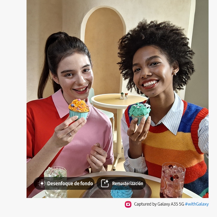 Dos personas sonriendo y sosteniendo magdalenas. Con opciones para Desenfoque de fondo, Remasterización. El texto dice Capturado con el Galaxy A35 5G #withGalaxy.