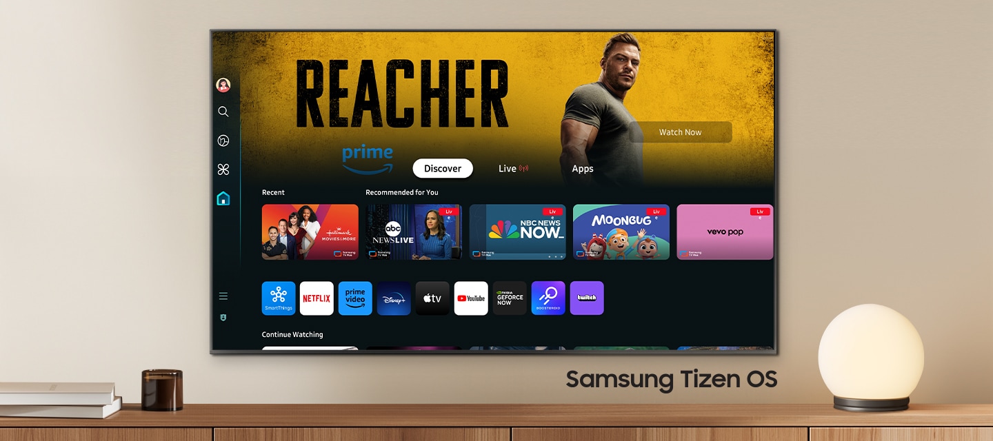 Un TV montado en la pared muestra aplicaciones populares y contenido seleccionado en el menú principal. Sistema operativo Tizen de Samsung