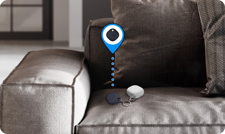 Se muestran unos Galaxy Buds en la esquina de un sofá con una SmartTag adherida. El icono virtual indica que la etiqueta ayuda a los usuarios a encontrar sus artículos.