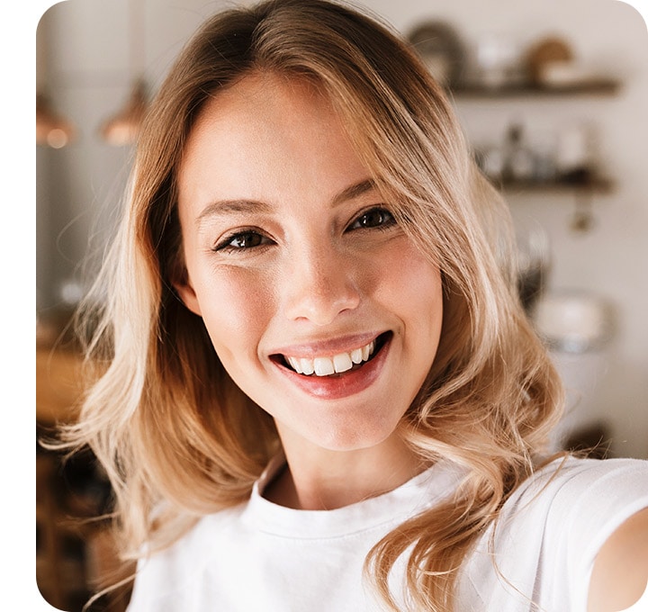 A woman taking a selfie. She's seen clearly but the background is blurred.