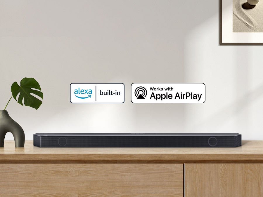 Alexa built-in logo and Works with Apple AirPlay logo with a Samsung Q series Soundbar sitting on top of a cabinet.