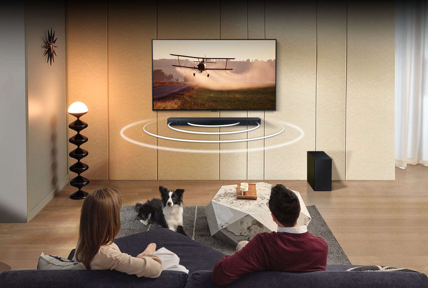 A man and woman are sitting in a living room with sound waves that come out of the Q60C's front speakers.