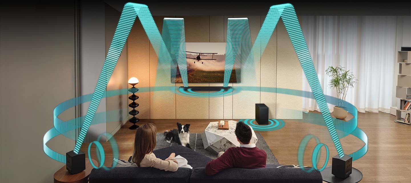 V obývacím pokoji sedí pár na pohovce a dívá se na televizi. Televize se instaluje na zeď a přímo pod ní se nachází Soundbar. Dvojice zadních reproduktorů je umístěna na bočních stolcích v zadní části místnosti. Zvukové vlny vycházejí z televizoru, Soundbaru a zadních reproduktorů z různých úhlů a šíří se v několika směrech, aby zaplnily místnost.