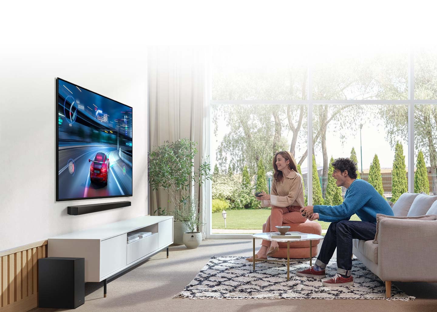 Muž a žena hrají závodní hru na svém televizoru, pod kterým je Soundbar, který poskytuje optimalizovaný zvuk s herním režimem.