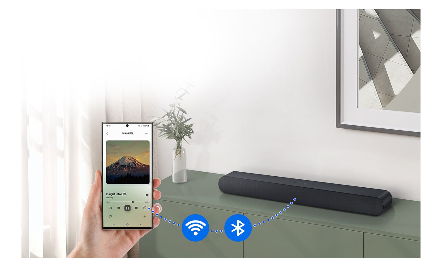 Smartphone je připojen k zařízení Soundbar pomocí tečkované čáry. Tečkovaná čára má ikony pro Wi-Fi a Bluetooth.