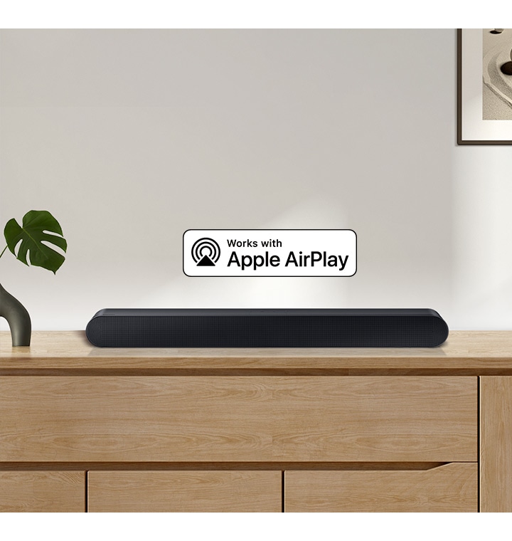 Soundbar Samsung je umístěn na horní straně skříně a je doplněn logem pro Works with Apple AirPlay.
