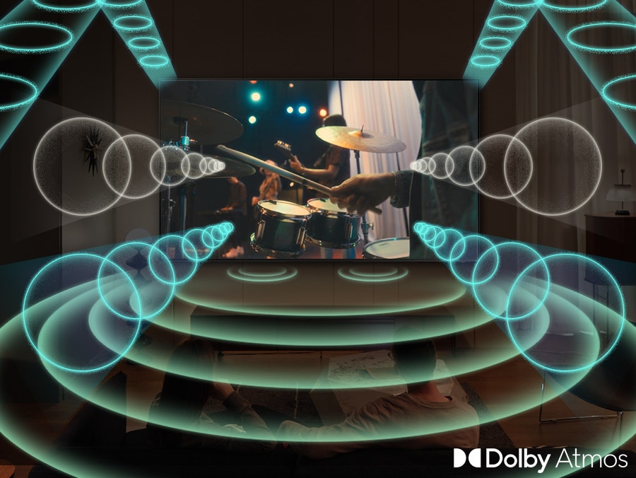 Televizor Samsung přehrává scénu vystupující kapely se zaměřením na bubeníka. Televizor vydává zvukové prstence v různých velikostech, které energicky pulzují a cestují všemi směry, aby zaplnily prostor, což naznačuje použití funkce Dolby Atmos.