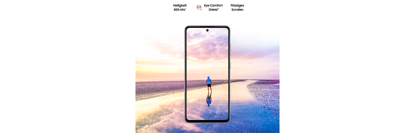 Das Galaxy A52 5G von vorne gesehen. Eine Szene eines Mannes, der bei Sonnenuntergang am Strand steht, verläuft über die Ränder des Displays hinaus. Der Text lautet: Helligkeit 800 Nits, Eye Comfort Shield mit SGS-Logo und Real Smooth.