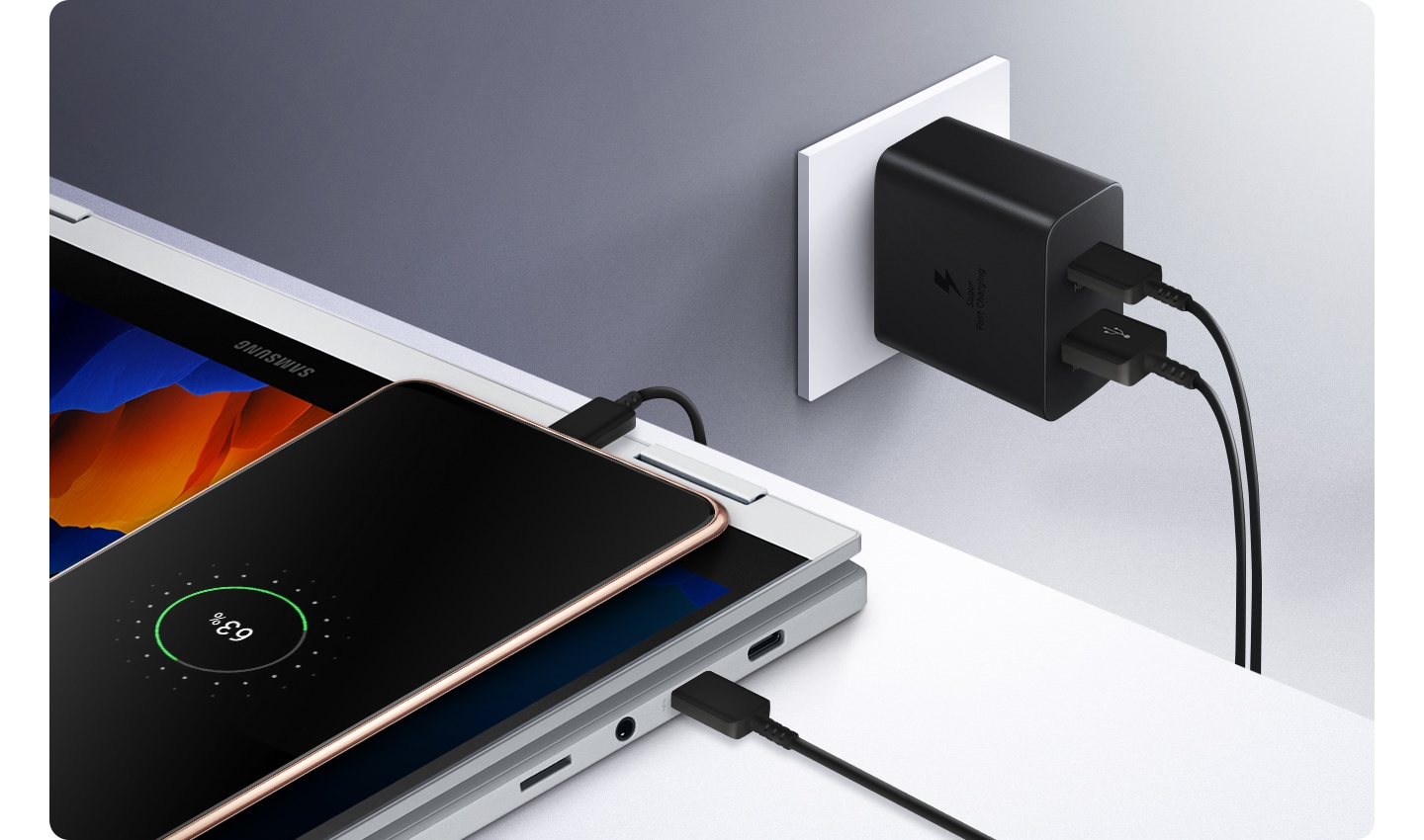 Der Power Adapter Duo ist an einer Steckdose in einer Wand eingesteckt und lädt ein Smartphone und einen Laptop gleichzeitig.