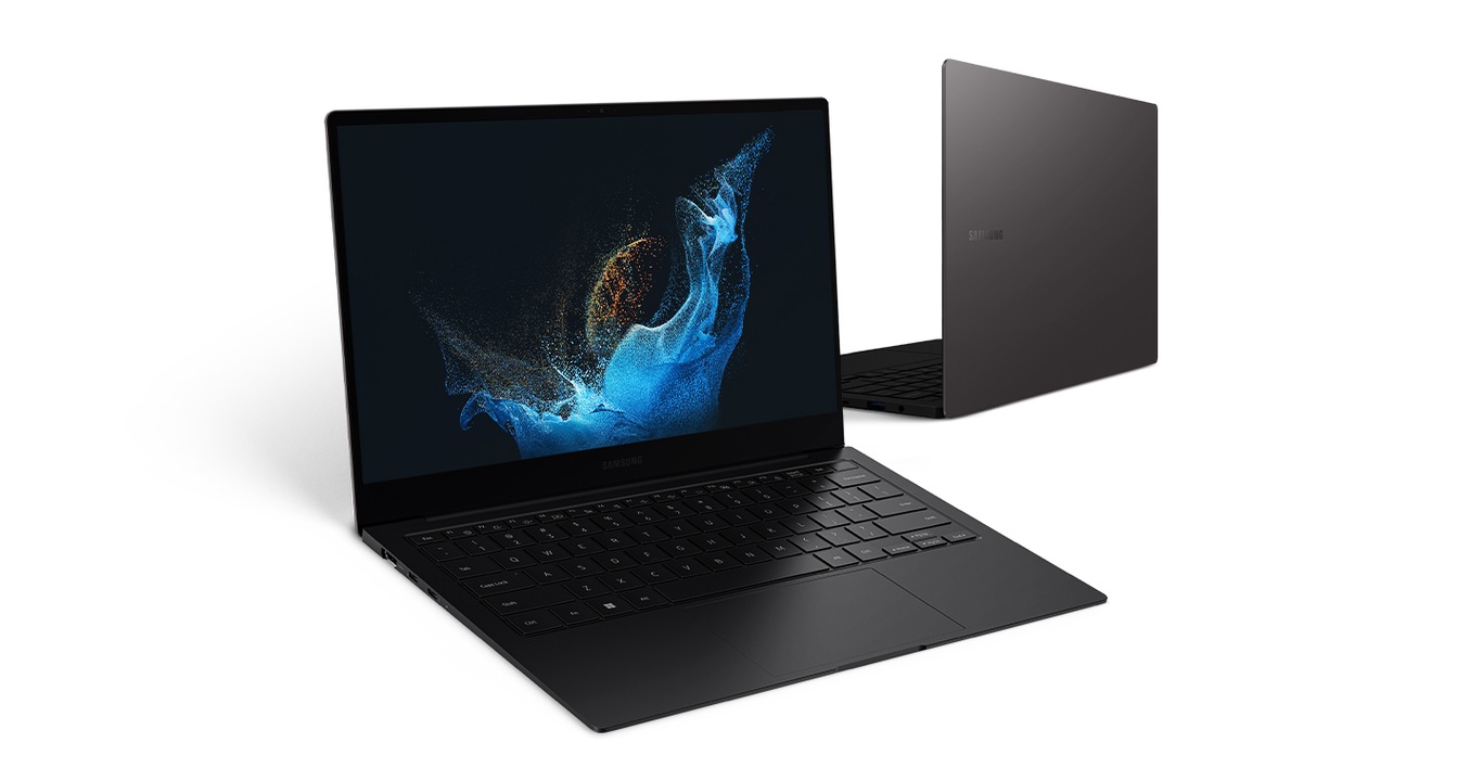 Two graphite-colored Galaxy Book2 Pro devices are next to each other facing opposite directions. The one on the left is open with green wavy wallpaper. The Galaxy Book2 Pro on the right is slightly behind the one on the left, facing back.