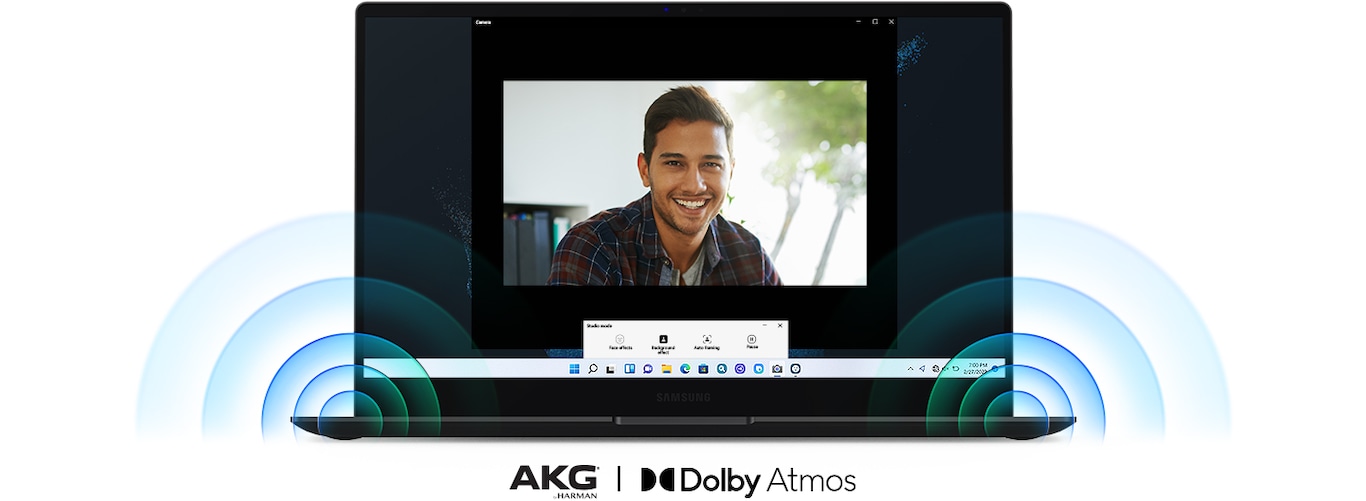 A Galaxy Book2 Pro is facing the front in the center with a man smiling during a video call.Powerful sound is coming out from the speakers on the bottom corners of the PC. Below the PC are two logos for AKG® by Harman and Dolby Atmos.