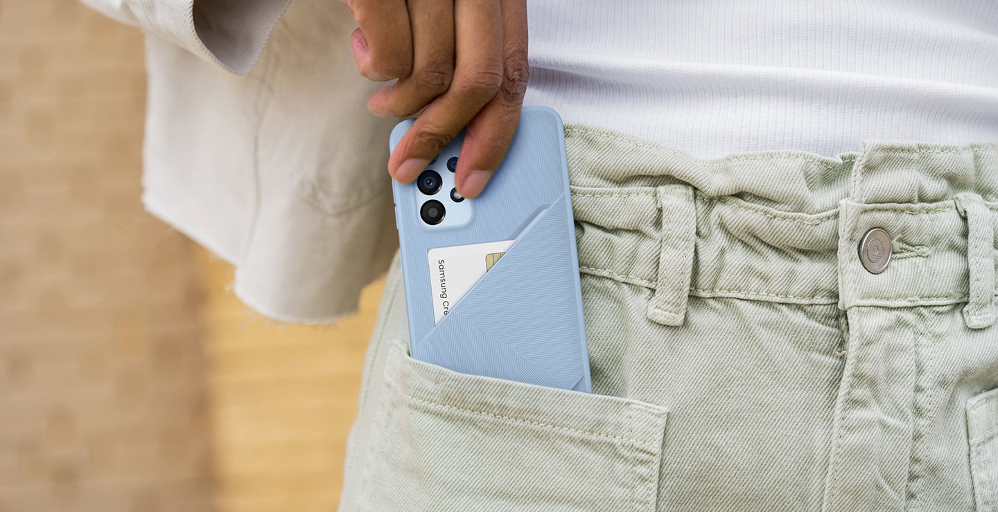 Galaxy A33 with an Arctic Blue Card Slot Cover is being slid into a user's pocket. A white, credit card can be seen inside the case's card slot.